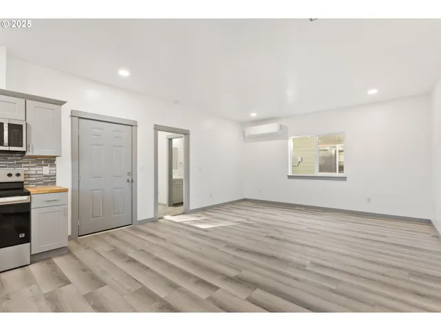 a view of an empty room with a window and a kitchen