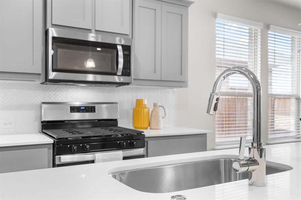 1864 Mensa Drive Haslet, TX 76052 - Photo 16 of 40 a kitchen with stainless steel appliances granite countertop a sink a stove and a microwave