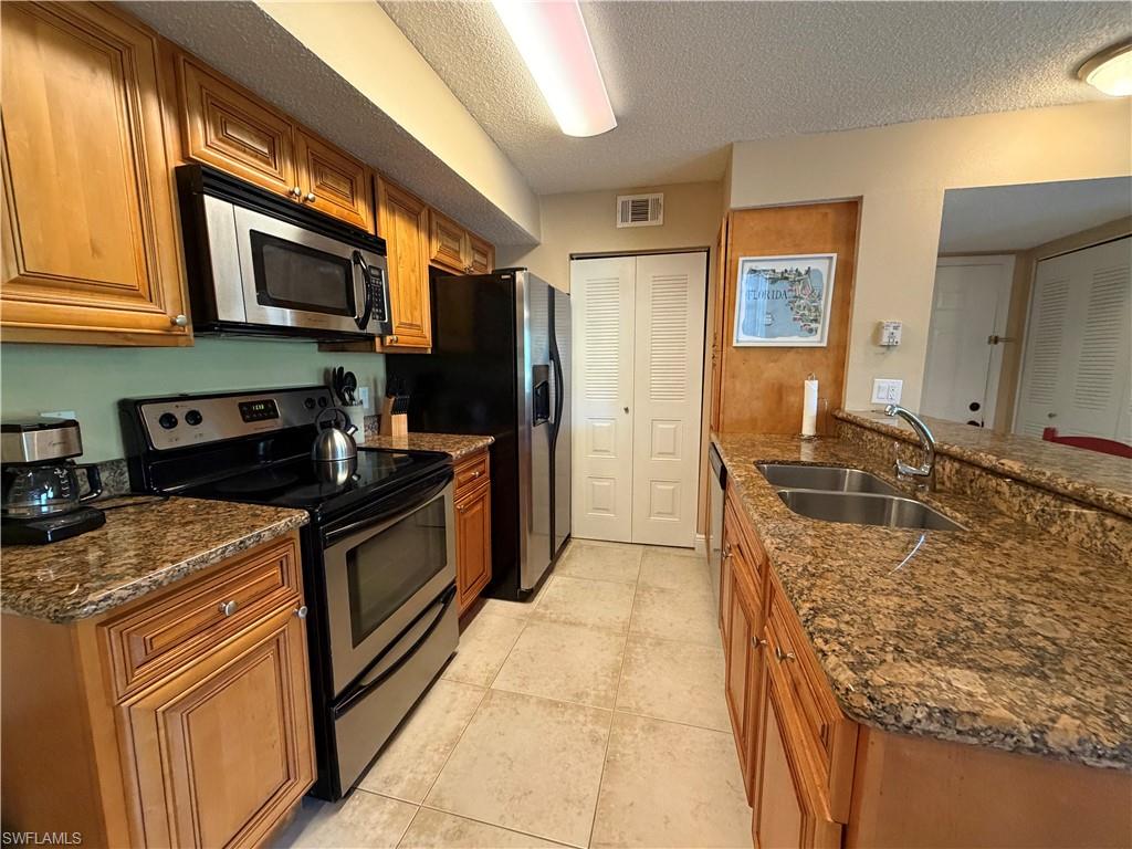 2070 Arbour Walk Circle, Unit 3214 Naples, FL 34109 - Photo 5 of 12 a kitchen with stainless steel appliances granite countertop a stove top oven a sink and dishwasher