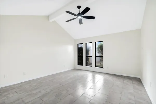an empty room with chandelier fan and windows