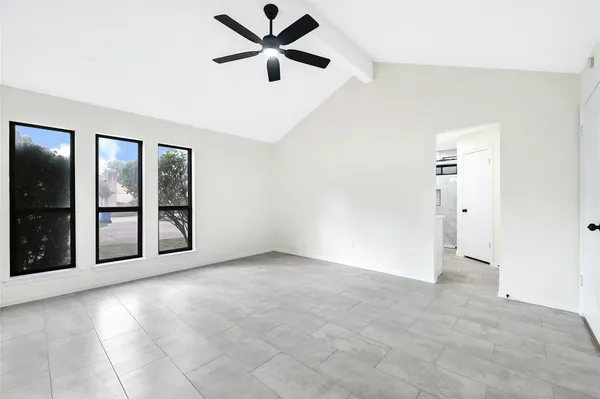 an empty room with chandelier fan and windows