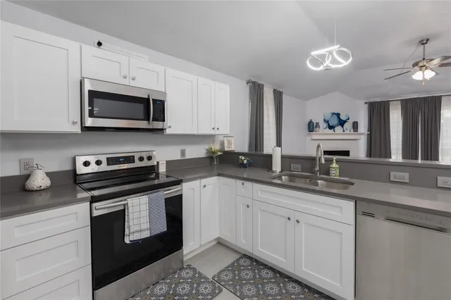 a kitchen with stainless steel appliances granite countertop a sink dishwasher stove and white cabinets