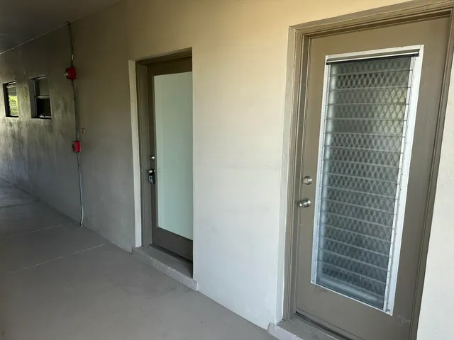 a view of an empty room with closet and mirror