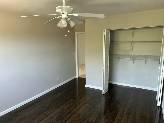 an empty room with wooden floor and fan
