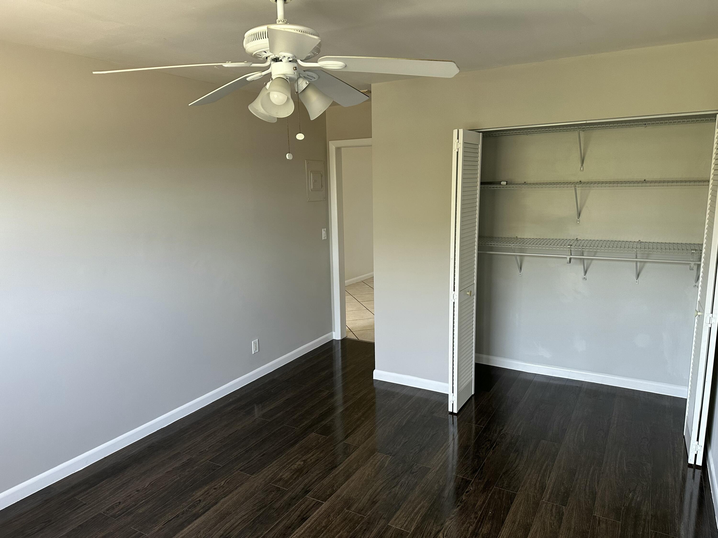 1480 East Sample Road, Unit 207 Pompano Beach, FL 33064 - Photo 8 of 14 an empty room with wooden floor and fan