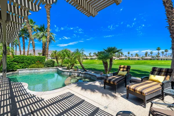 a view of a swimming pool and lounge chairs in back yard of the house