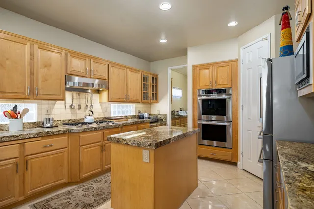 a kitchen with kitchen island granite countertop a refrigerator stove top oven and sink