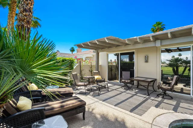 a view of a patio with couches table and chairs under an umbrella with potted plants