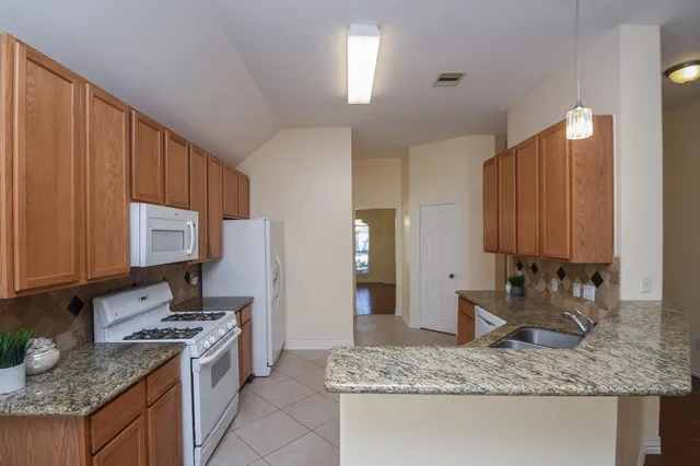 a kitchen with kitchen island granite countertop a sink stove and cabinets