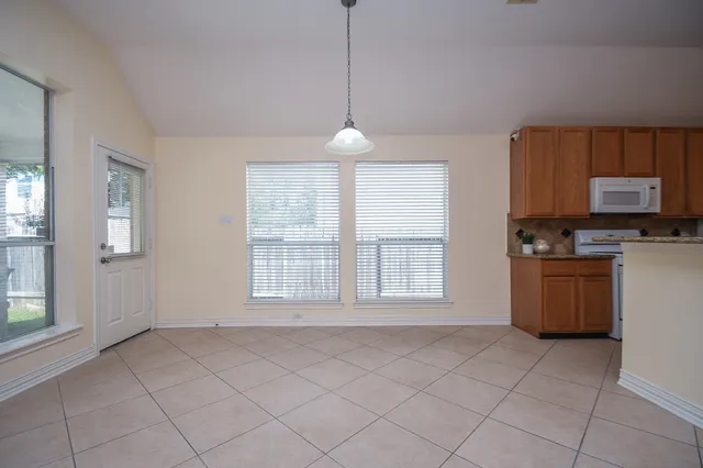 a view of a kitchen and an empty room with a window