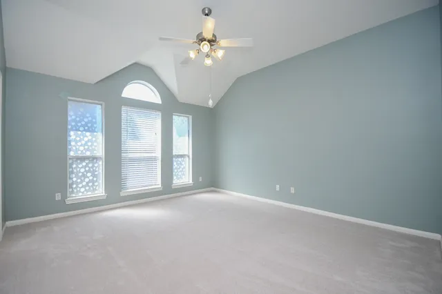 an empty room with windows and chandelier fan