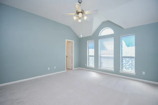an empty room with windows and chandelier fan