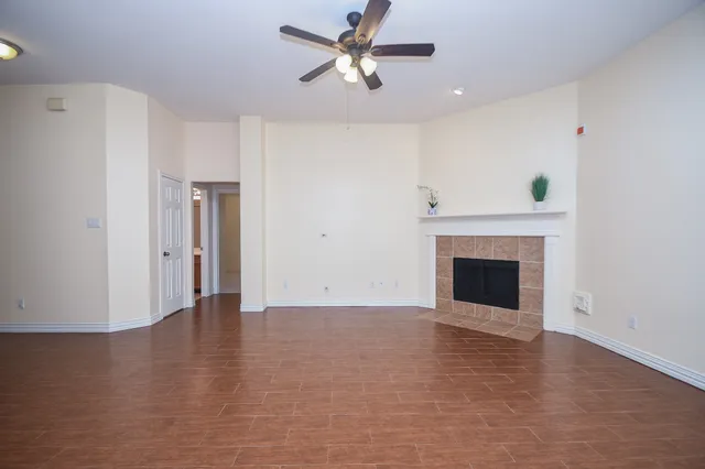 a view of an empty room with a fireplace and a fan