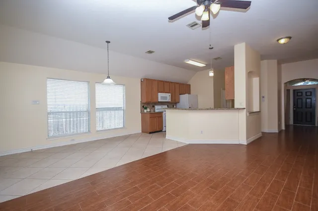 a view of a kitchen with a kitchen island wooden floor and a ceiling fan