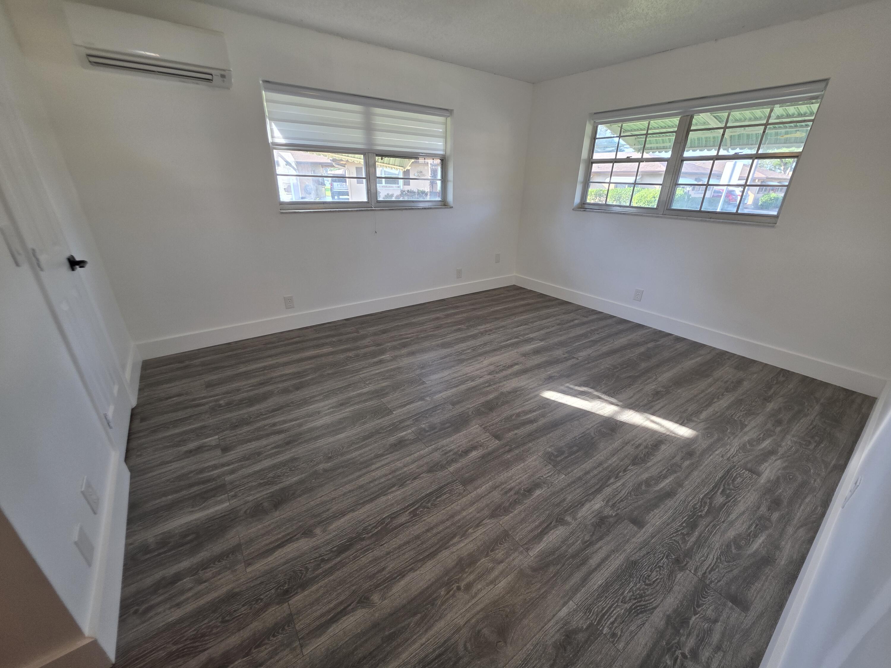 718 Whippoorwill Lane Delray Beach, FL 33445 - Photo 14 of 38 wooden floor in an empty room with a window