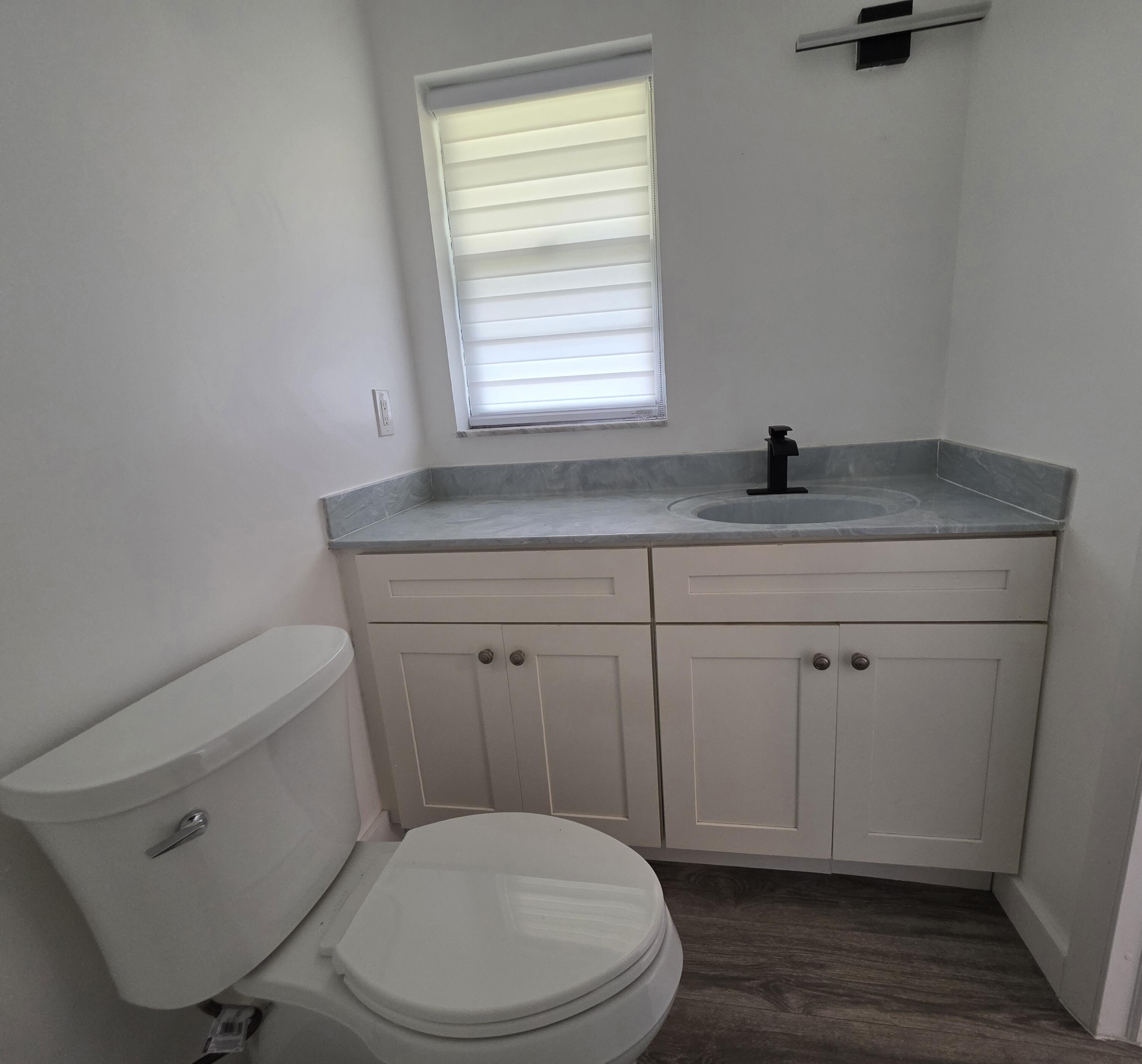 718 Whippoorwill Lane Delray Beach, FL 33445 - Photo 19 of 38 a bathroom with a toilet a sink a window and mirror