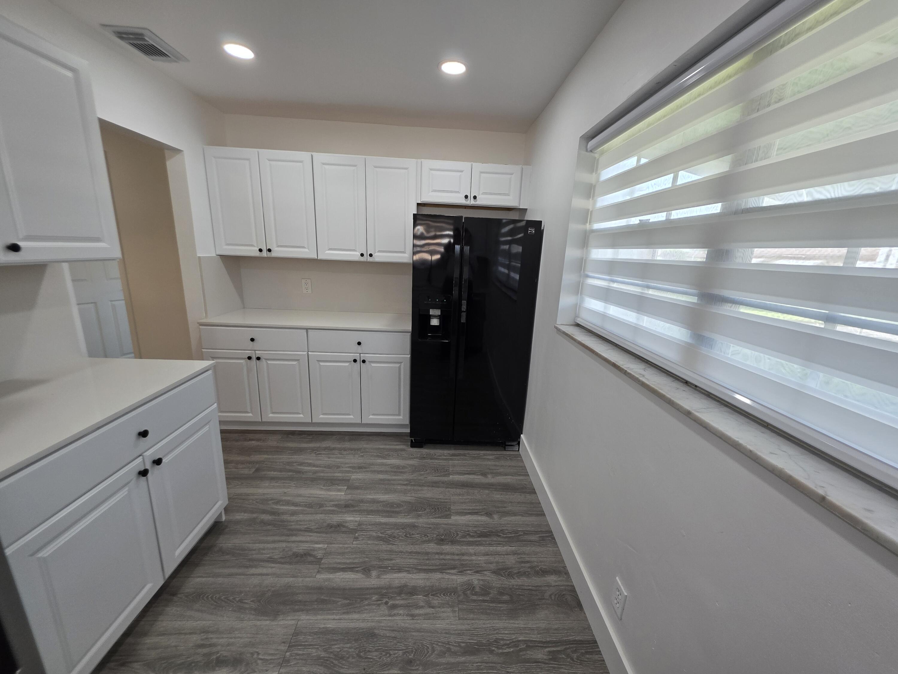 718 Whippoorwill Lane Delray Beach, FL 33445 - Photo 7 of 38 a kitchen with a refrigerator and window