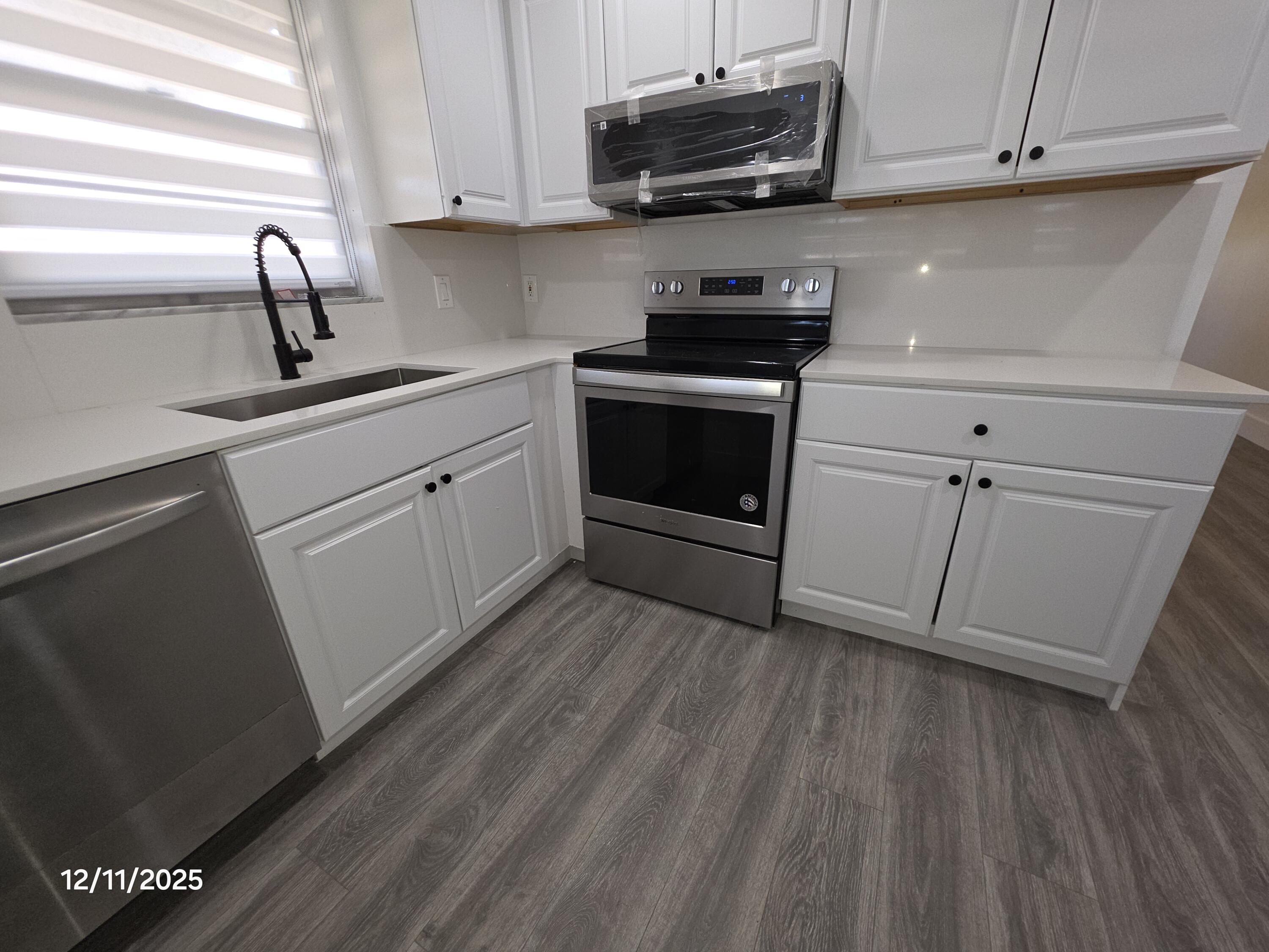 718 Whippoorwill Lane Delray Beach, FL 33445 - Photo 8 of 38 a kitchen with a sink a microwave and cabinets