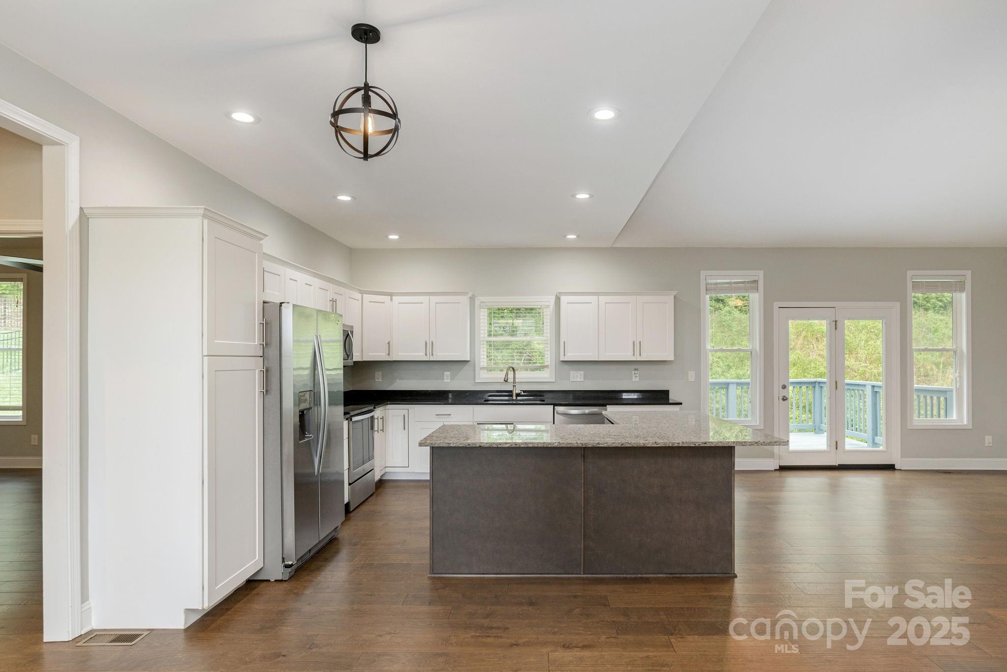 76 Tryon View Drive Flat Rock, NC 28731 - Photo 13 of 30 a kitchen with stainless steel appliances granite countertop a stove a sink a refrigerator white cabinets and a wooden floor