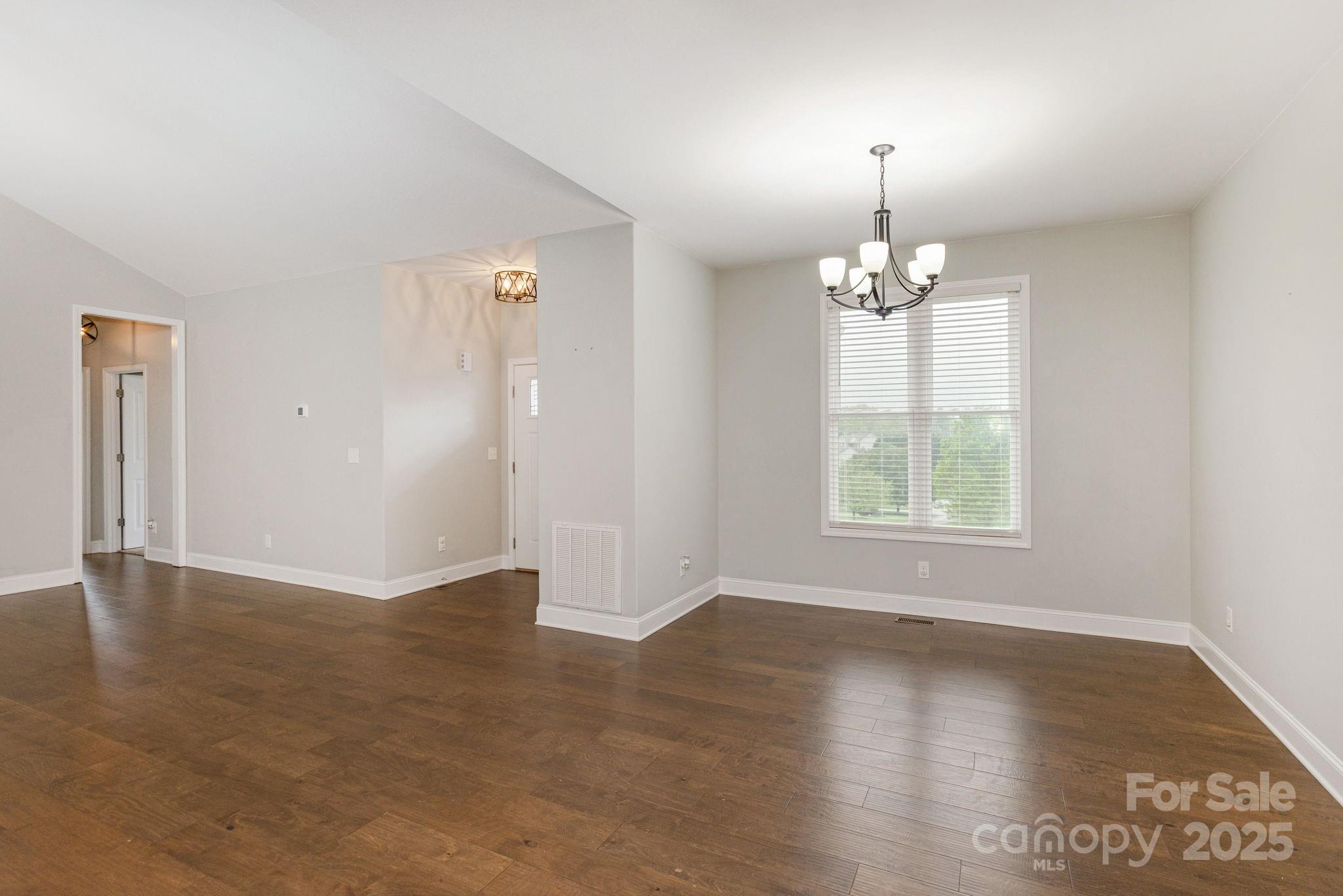 76 Tryon View Drive Flat Rock, NC 28731 - Photo 4 of 30 an empty room with wooden floor chandelier and windows