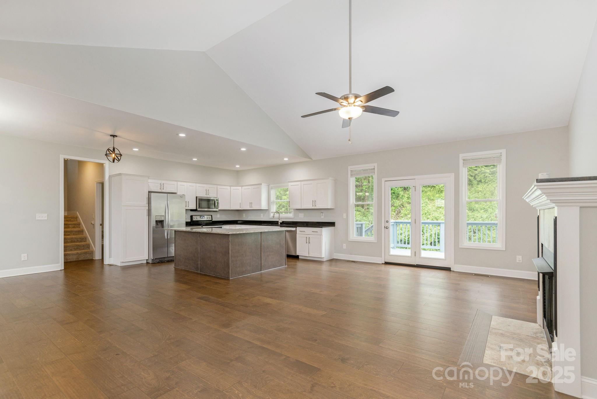 76 Tryon View Drive Flat Rock, NC 28731 - Photo 9 of 30 a large kitchen with stainless steel appliances granite countertop a stove a refrigerator a sink dishwasher with a dining table and chairs with wooden floor