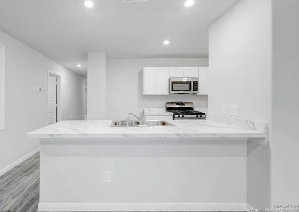 a kitchen with a sink and a stove top oven with wooden floor