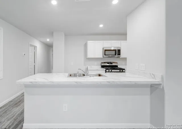 a kitchen with a sink and a stove top oven with wooden floor
