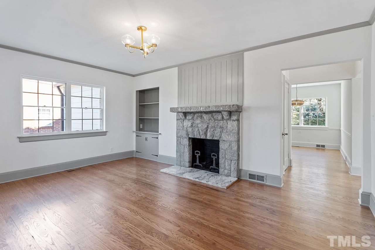 704 Dixie Trail Raleigh, NC 27607 - Photo 7 of 31 a view of an empty room with wooden floor fireplace and a window