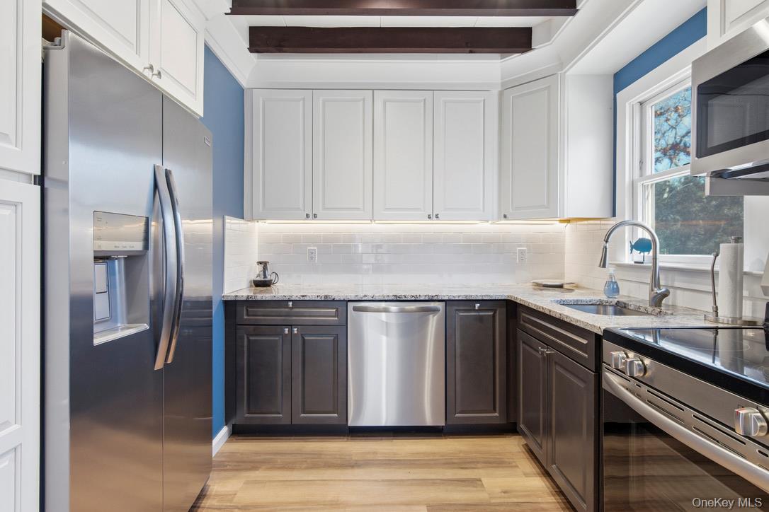 3 Foster Avenue Hampton Bays, NY 11946 - Photo 6 of 20 a kitchen with stainless steel appliances granite countertop a sink stove and refrigerator