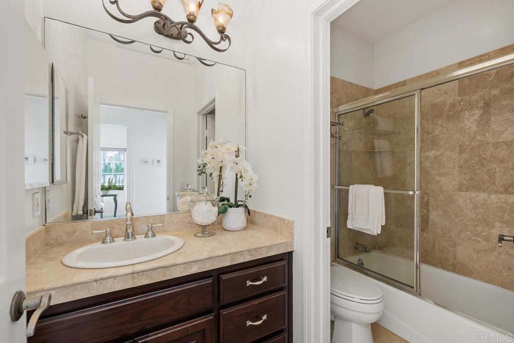 6456 Franciscan Road Carlsbad, CA 92011 - Photo 32 of 43 a bathroom with a granite countertop sink a toilet a mirror and shower