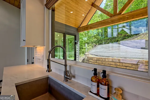 a view of a kitchen with kitchen island a large window cabinets a sink and stainless steel appliances