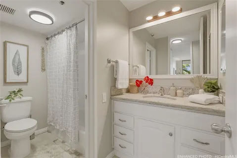 a bathroom with a granite countertop sink mirror vanity and toilet