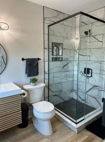 a bedroom with a bed and a lamp on table with wooden floor