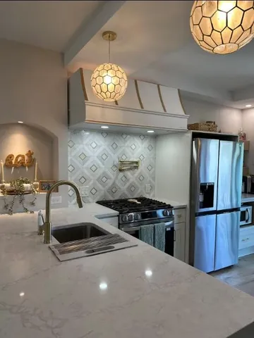a kitchen with stainless steel appliances a stove refrigerator and a sink