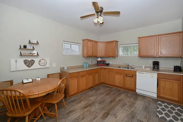 a kitchen with stainless steel appliances granite countertop a sink dishwasher cabinets a dining table and chairs with wooden floor