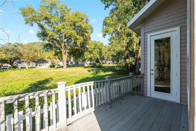 a view of a deck with wooden floor and fence next to a yard
