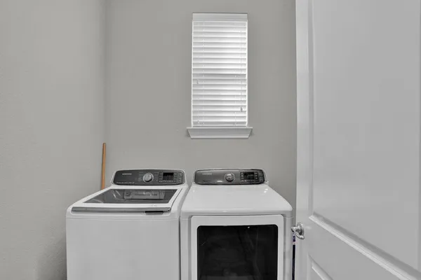 a view of washer and dryer with bathroom in the background