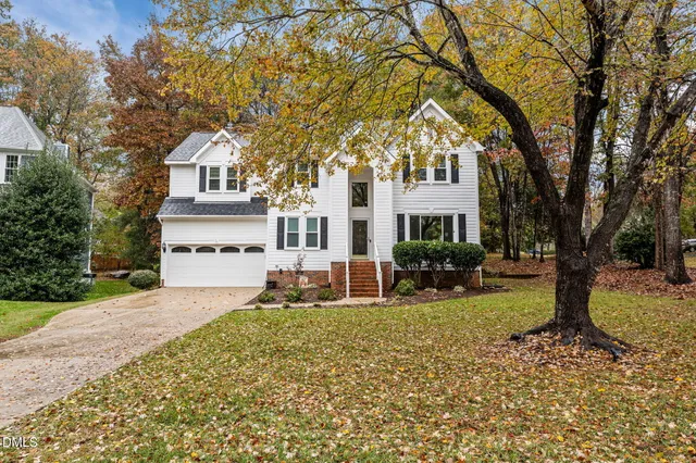 a front view of a house with garden and trees