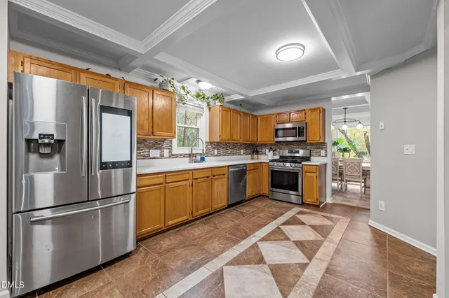 a kitchen with stainless steel appliances granite countertop a refrigerator a sink dishwasher a stove and white countertops with wooden floor