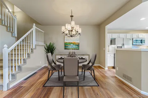a dining room with wooden floor a chandelier a wooden table and chairs