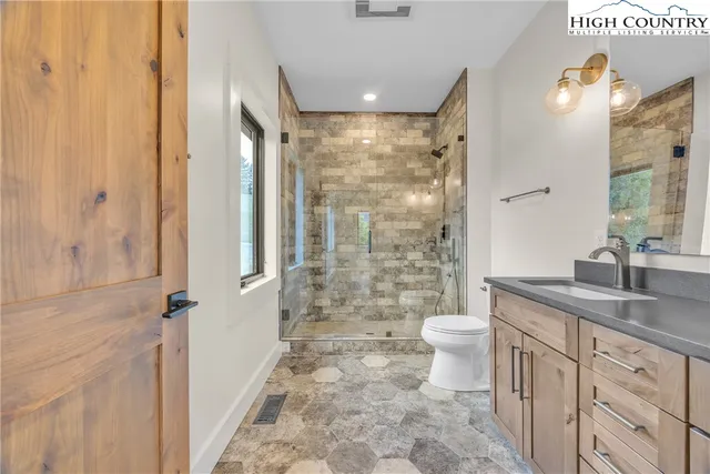 a bathroom with a granite countertop bathtub shower sink vanity and toilet