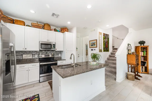 a kitchen with stainless steel appliances granite countertop a refrigerator and a stove top oven