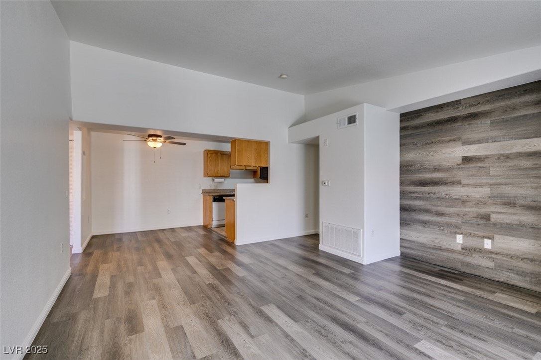 3318 North Decatur Boulevard, Unit 2138 Las Vegas, NV 89130 - Photo 6 of 40 Unfurnished living room with wood finished floors, ceiling fan, baseboards, and vaulted ceiling