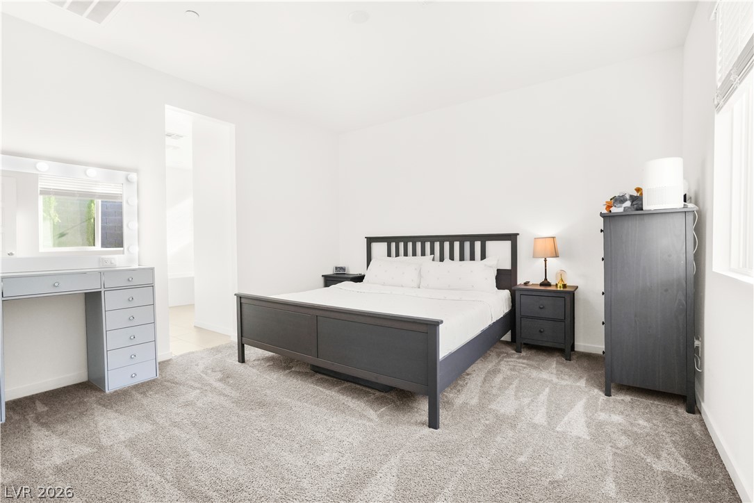 9398 Noble Fir Rdg Court Las Vegas, NV 89143 - Photo 13 of 36 A well-lit bedroom features plush carpeting and a spacious dressing area.