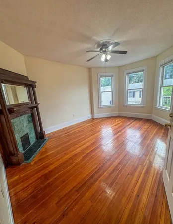 a view of empty room with wooden floor and fan
