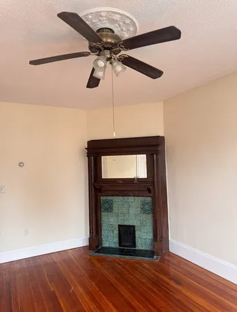 a view of an empty room with wooden floor fireplace and a window