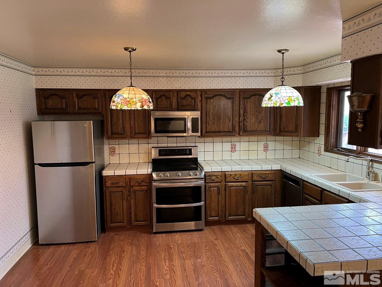 1840 Allen Street Reno, NV 89509 - Photo 5 of 20 a kitchen with stainless steel appliances granite countertop a sink a stove a refrigerator and a wooden floor