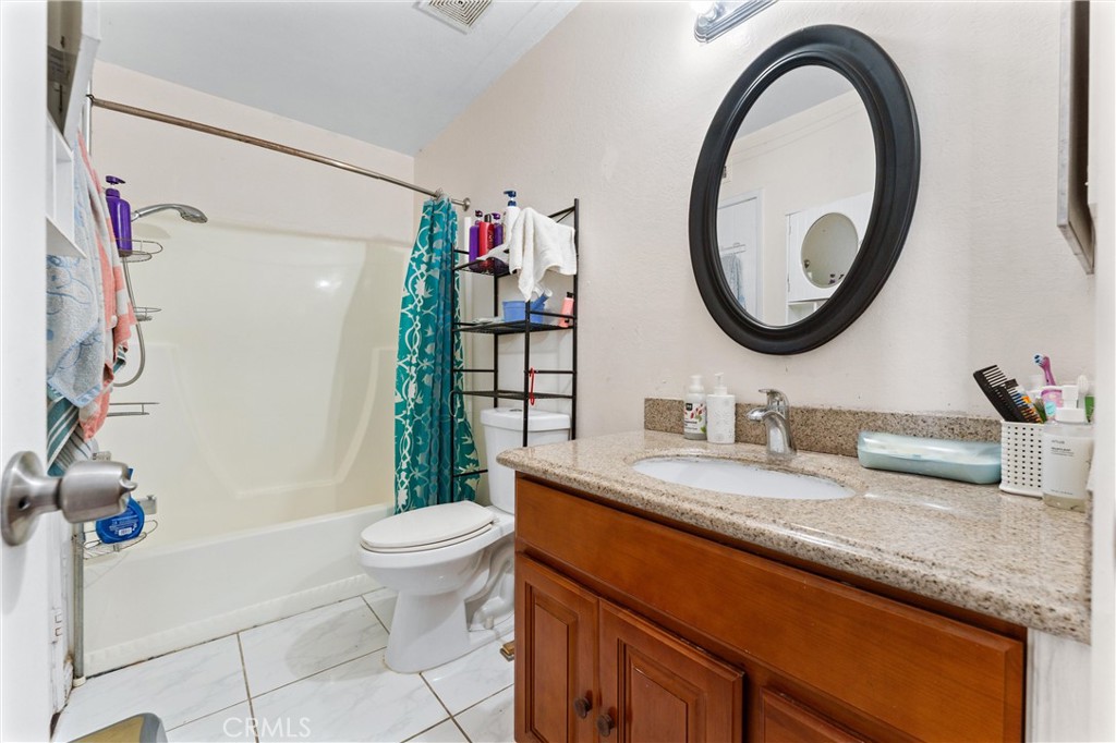 3927 West McFadden Avenue, Unit B Santa Ana, CA 92704 - Photo 10 of 14 a bathroom with a granite countertop toilet a sink and a mirror
