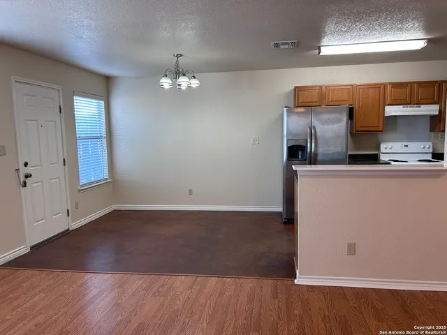 an empty room with wooden floor cabinet and windows
