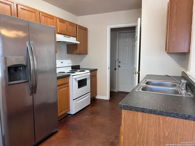 a kitchen with stainless steel appliances granite countertop a refrigerator a stove and a sink with wooden floor